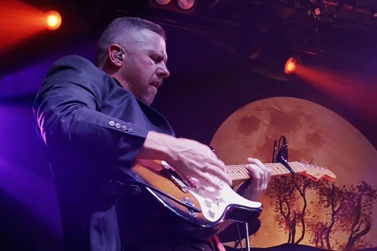 Mitchell Jon playing a Fender Strat guitar with moon backdrop and stage lights