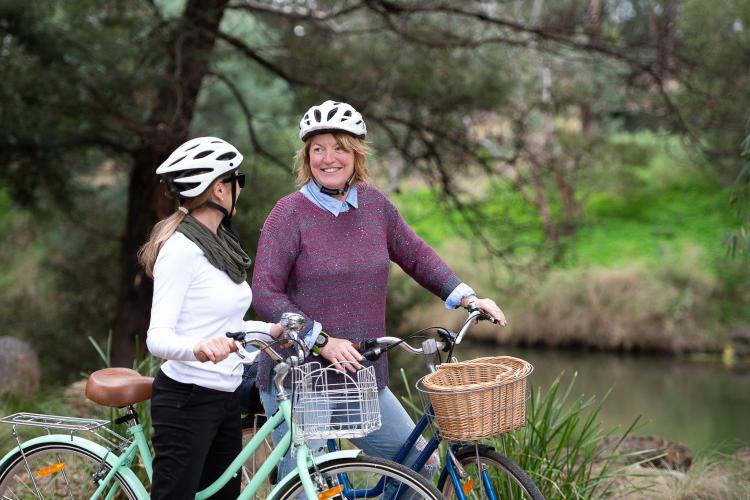 two adults standing next to Werribee River with bicycles