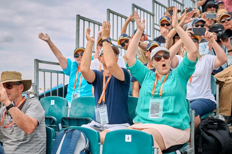 Gold Pass Grandstand ticketholders holding up their arms in celebration