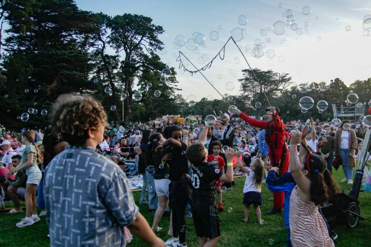 children gathered around performer blowing bubbles