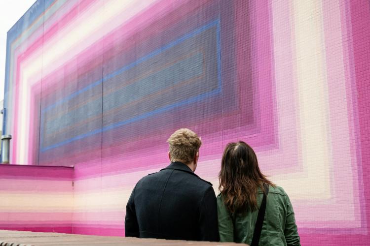 two adults looking at street art Pink Hum by DREZ