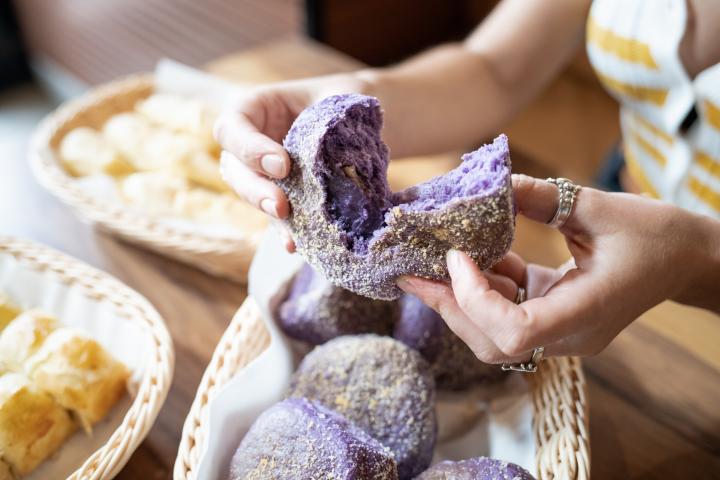 close up of hands breaking apart ube flavoured dessert