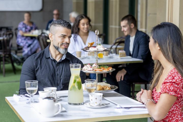 adults smiling at one another at table with high tea