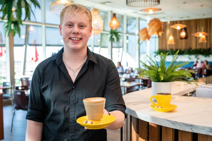 a barista holding a cup of coffee and smiling